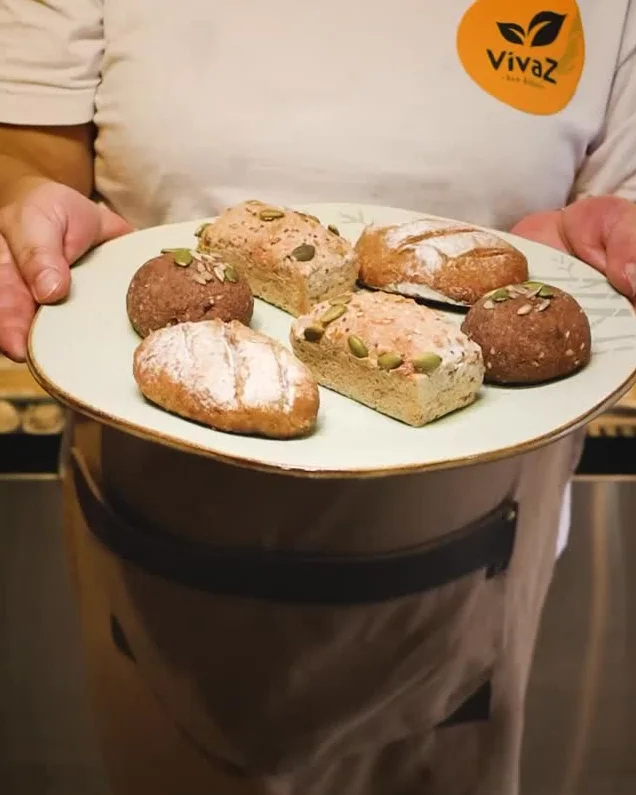 Atendente da Vivaz segurando um prato de doces e pães sem glúten